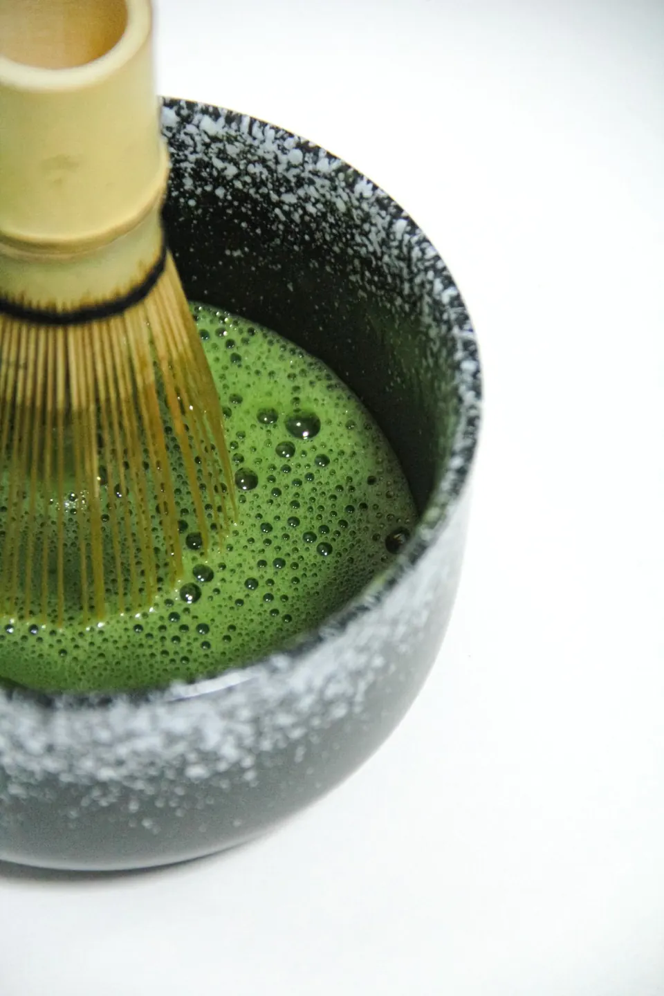 Whisking matcha in a stoneware bowl with a bamboo chasen